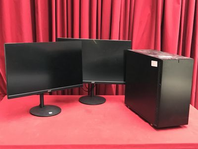 deux écrans d'ordinateur posés sur une table devant des rideaux rouges