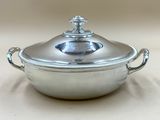 une cocotte en argent avec un couvercle posée sur une table