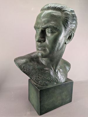 statue of a man ' s head on a pedestal with a vase in the background