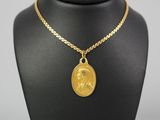 a gold necklace with a coin on a mannequin neck