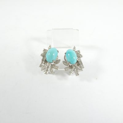 une paire de boucles d'oreilles en turquoise et argent posées sur un fond blanc