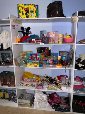 une bibliothèque blanche remplie de jouets et d'autres objets