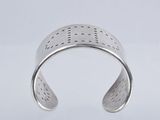 a close up of a silver cuff with holes on it