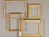 three gold picture frames hanging on a wall in a room