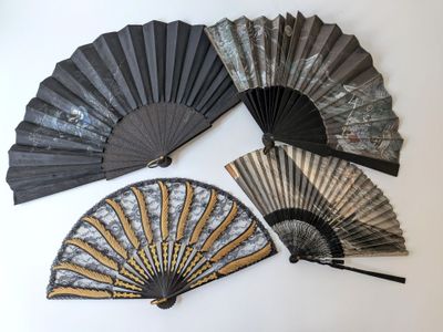 trois éventails noirs et dorés sont posés sur une surface blanche