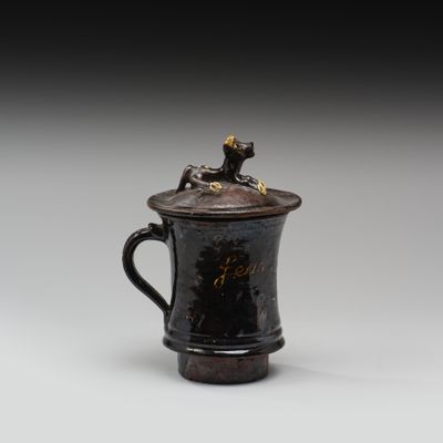 une image représentant une tasse noire sur laquelle est posé un chien
