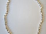 gros plan d'un collier de perles blanches sur une surface blanche