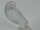 a glass figurine of a bird on a clear base
