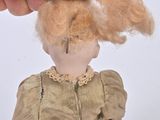 a hand holding a doll with a hairdof on top of it