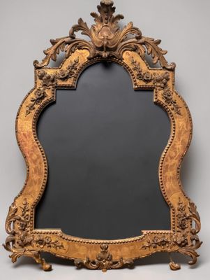 an ornately carved mirror with a black background and a gold frame