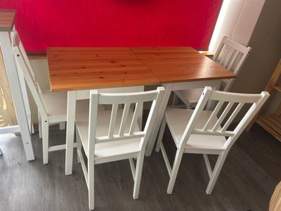 a table and four chairs in a room with a clock on the wall