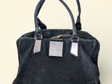 black sued handbag with silver metal accents on a white background