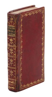 un vieux livre à la couverture rouge posé sur une surface blanche