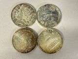 four different coins sitting on top of each other on a white surface