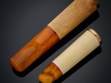pair of carved bone and wood smoking pipes on a black background