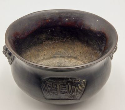 a black bowl with a handle on a white surface