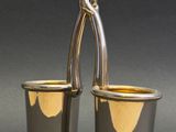 deux tasses en argent avec des anses sur fond gris