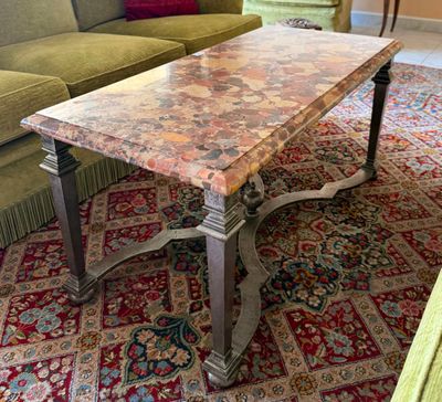 une table basse avec un plateau en marbre posée sur un tapis dans un salon