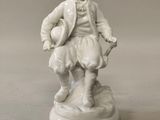 a white figurine of a man with a hat and coat