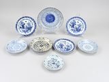 an assortment of blue and white plates and bowls on a white surface