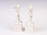 pair of white figurines of a boy and a girl on pedestals