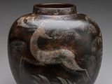 l'image d'un vase orné d'un oiseau, posé sur une surface grise