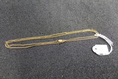 a gold chain with a tag attached to it on a black surface