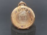 a gold pocket watch sitting on top of a black table