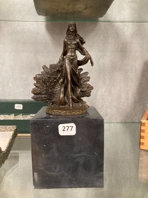 a bronze statue of a woman holding a bird on a pedestal