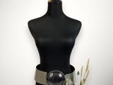 un mannequin noir avec une ceinture argentée et un vase rempli de fleurs