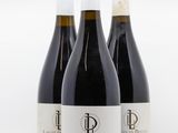 trois bouteilles de vin posées les unes à côté des autres sur une surface blanche