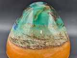 a picture of a green and orange vase on a black surface