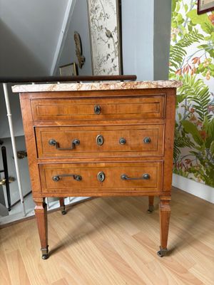 une commode en bois avec un plateau en marbre dans une pièce