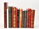 several old books are lined up in a row on a white surface