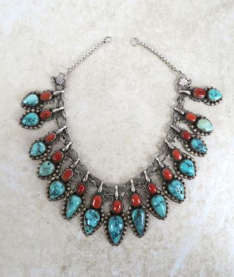 un collier orné de pierres turquoise et rouges sur fond blanc