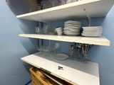 une étagère sur laquelle sont posés de la vaisselle et des verres, dans un coin de la pièce