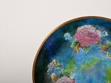 a plate with flowers painted on it sitting on a table