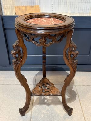 une vieille table en bois avec un plateau en marbre, posée sur un sol carrelé