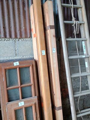 une échelle appuyée contre un mur, à côté d'un tas de vieilles fenêtres