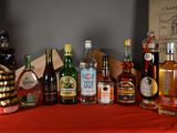 many bottles of alcohol on a table with a red table cloth