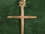 une croix en or ornée d'un oiseau, posée sur un tissu vert