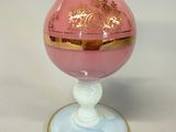 a pink glass vase with a gold rim on a white surface