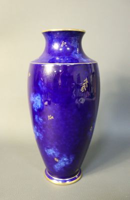 a blue vase sitting on a table with a white wall in the background