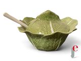 a green cabbage bowl with a wooden spoon in it