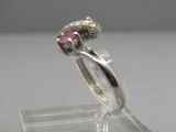 une bague sertie d'une pierre rose, montée sur un support transparent