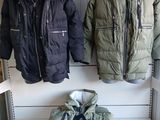 two jackets and a bag on a shelf in a room