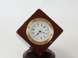 a small clock on a wooden stand on a white surface