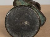 an antique bronze figurine of a man with a hat on his head