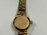 an image of a gold wrist watch with a coin on it