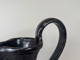 a black pitcher sitting on a table with a white background